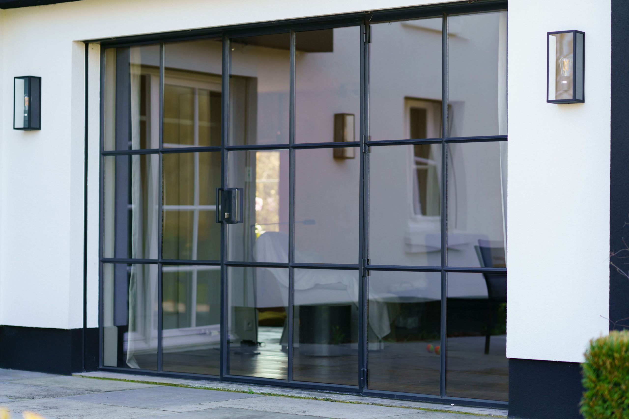 Baie vitrée en acier sur mesure noire avec croisillons pour une habitation contemporaine au style industriel
