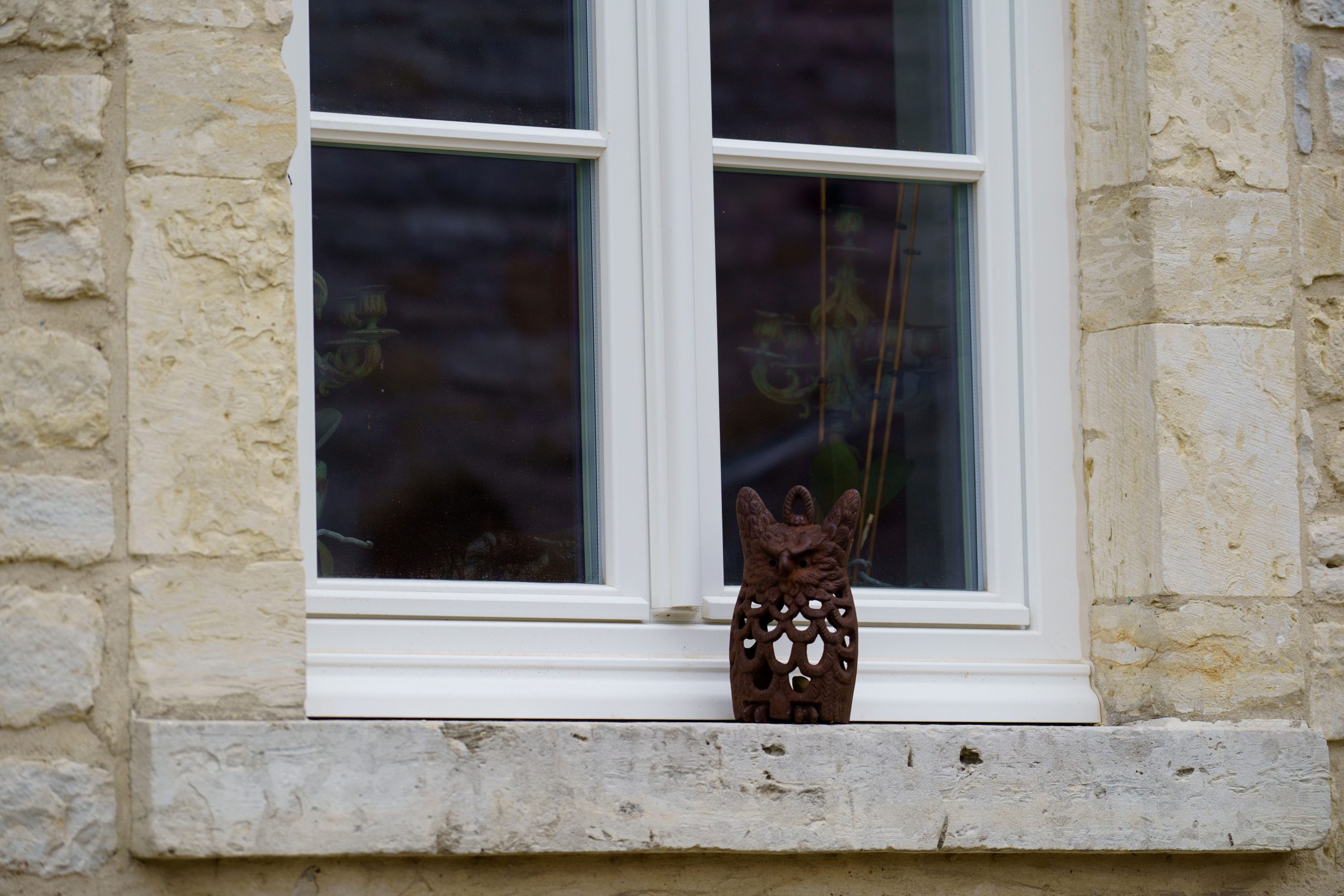 Fenêtre PVC blanche sur mesure installée sur une façade en pierre naturelle dans le respect du style traditionnel de l’habitation